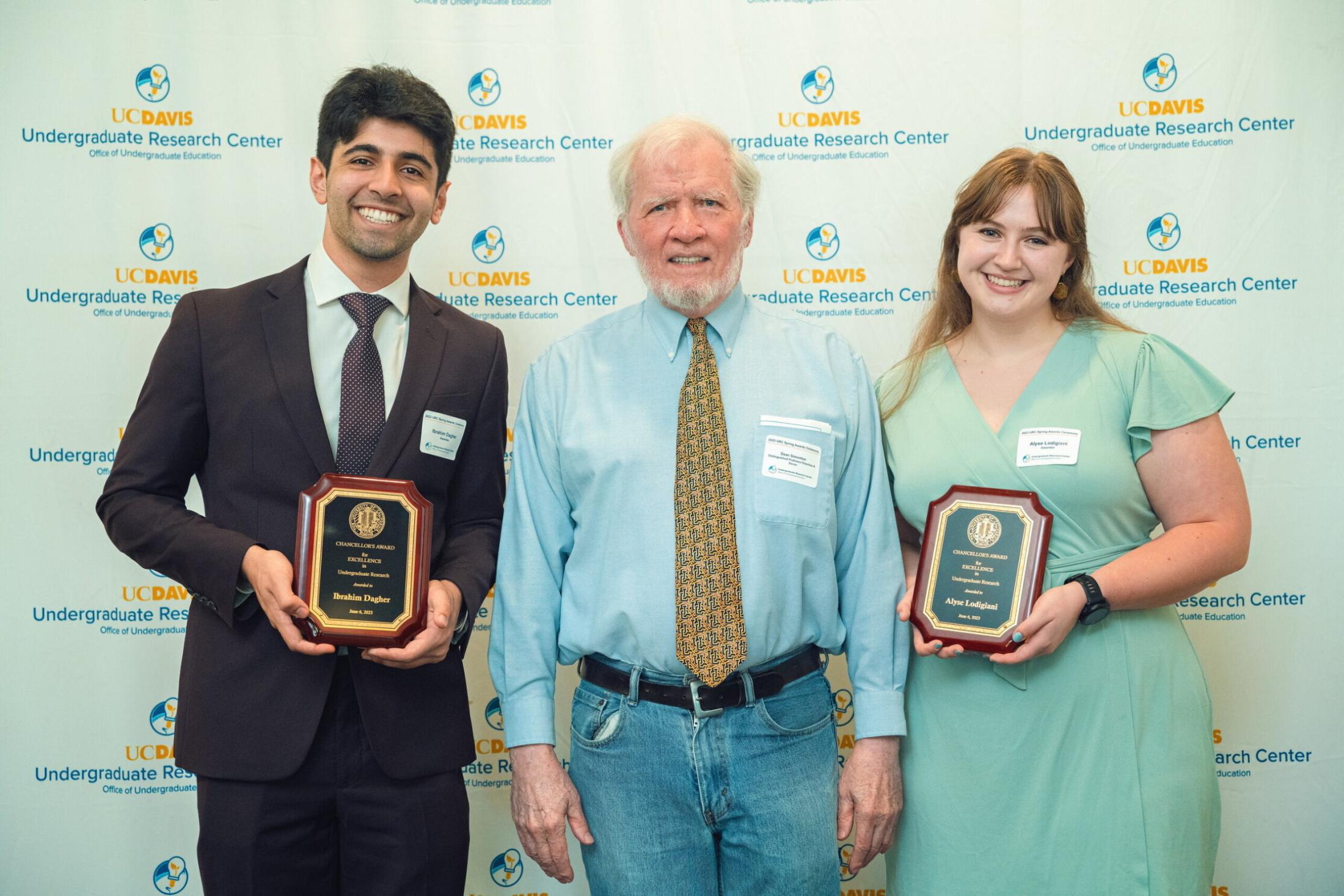 Dean Keith Simonton stands in between two students holding awards