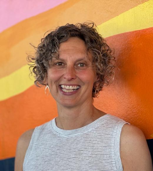 Headshot of a woman with a colorful background behind her