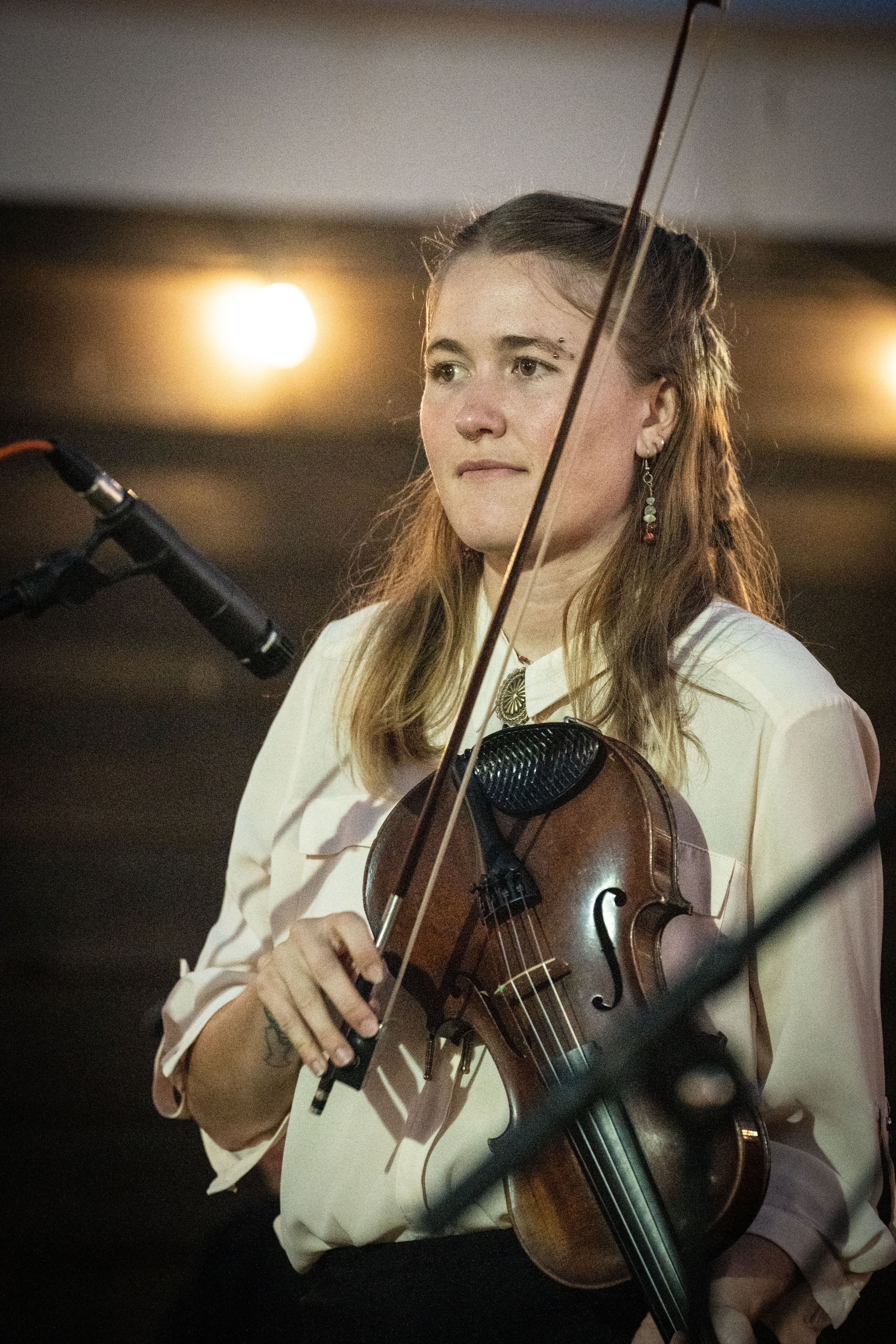 A person holds a fiddle and bow in their hand. 