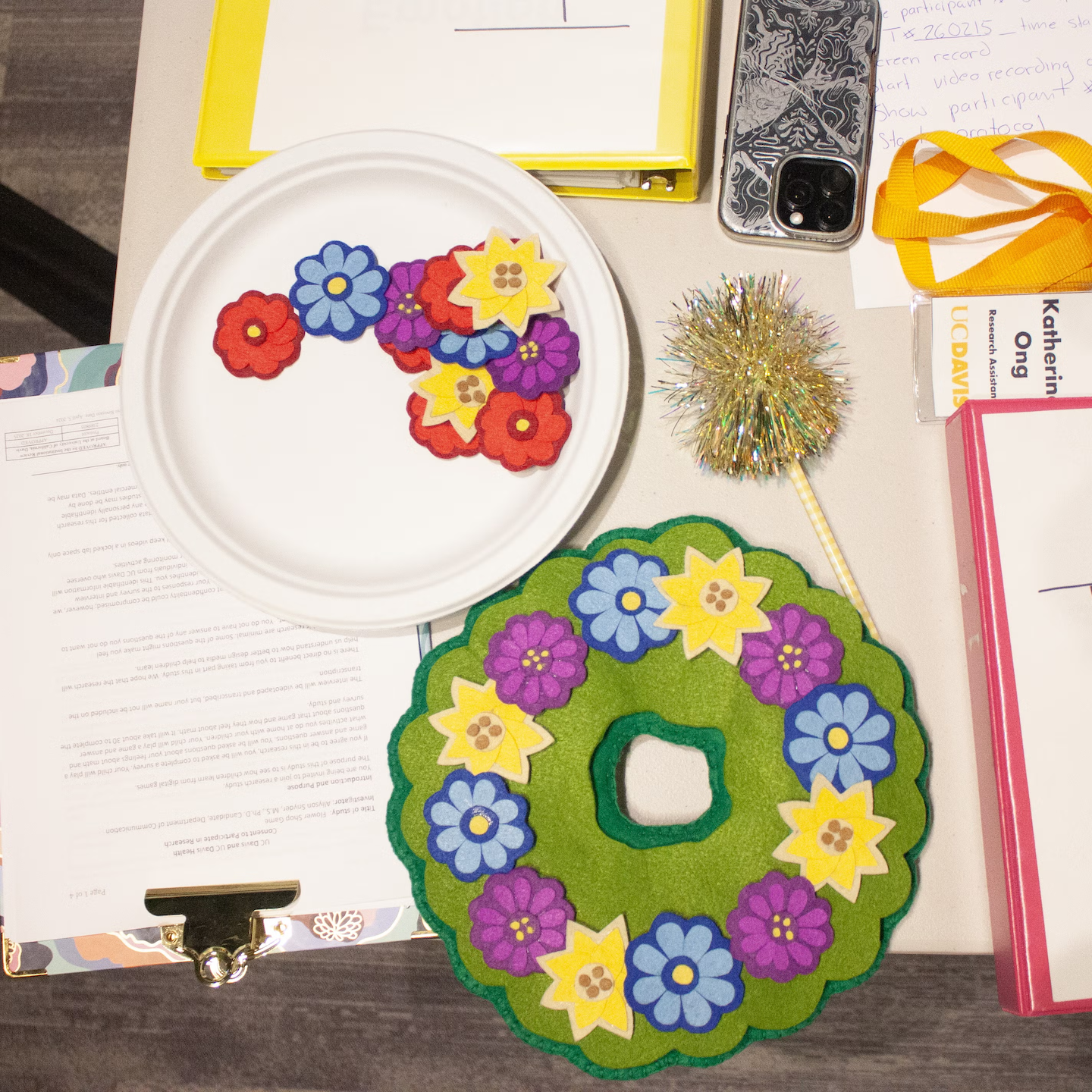 Top-down view of colorful felt flower wreath and loose felt flowers on craft table