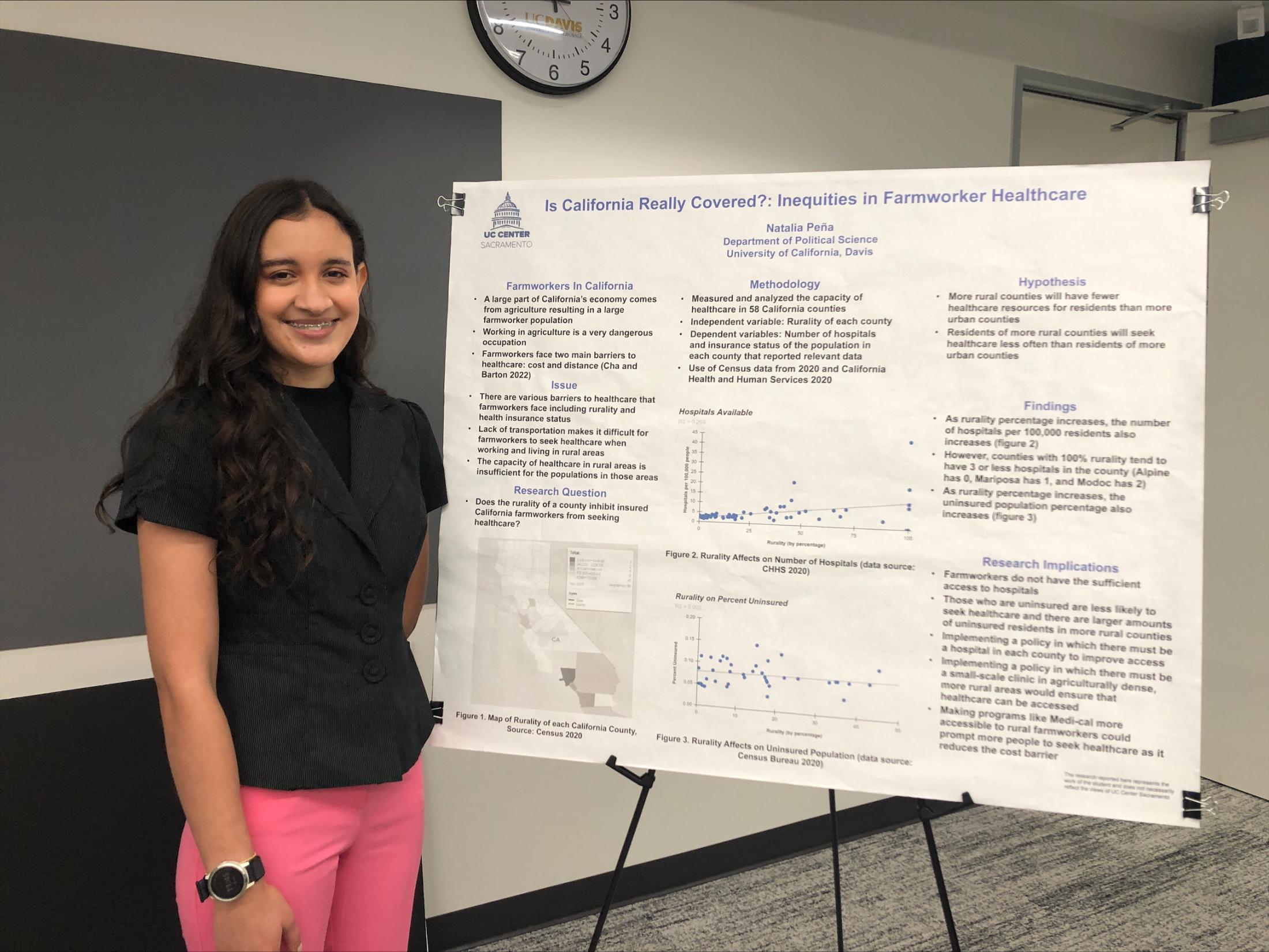 Natalia Peña, stands in front of her poster board at  the UC Center Sacramento Undergraduate Research Showcase. 