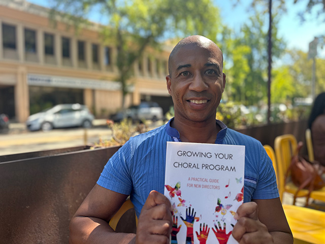 Nicolás Dosman looks towards the camera while holding his newly published book