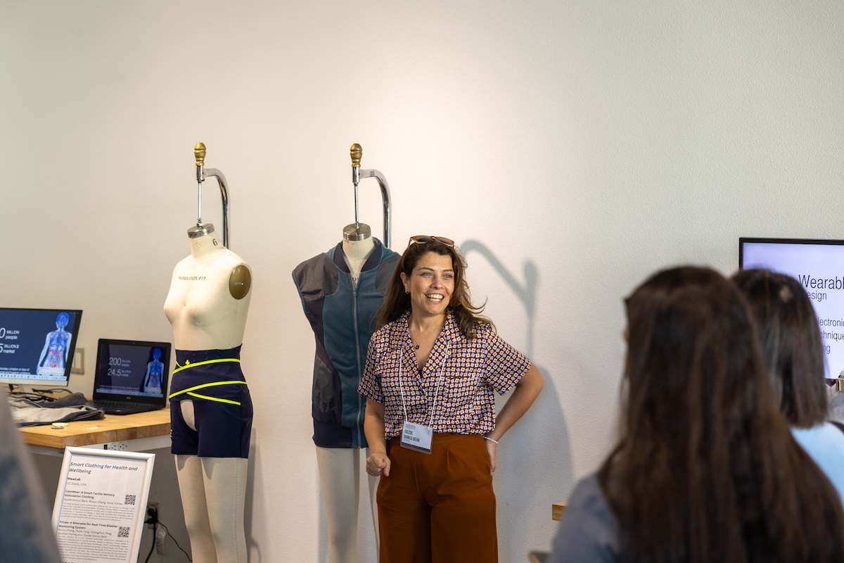 Gozde Goncu-Berk stands in front of mannequins, which display a couple of her wearable projects. 