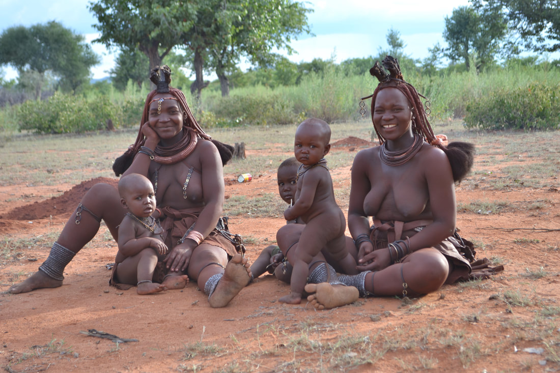 A Himba family sits on the ground 