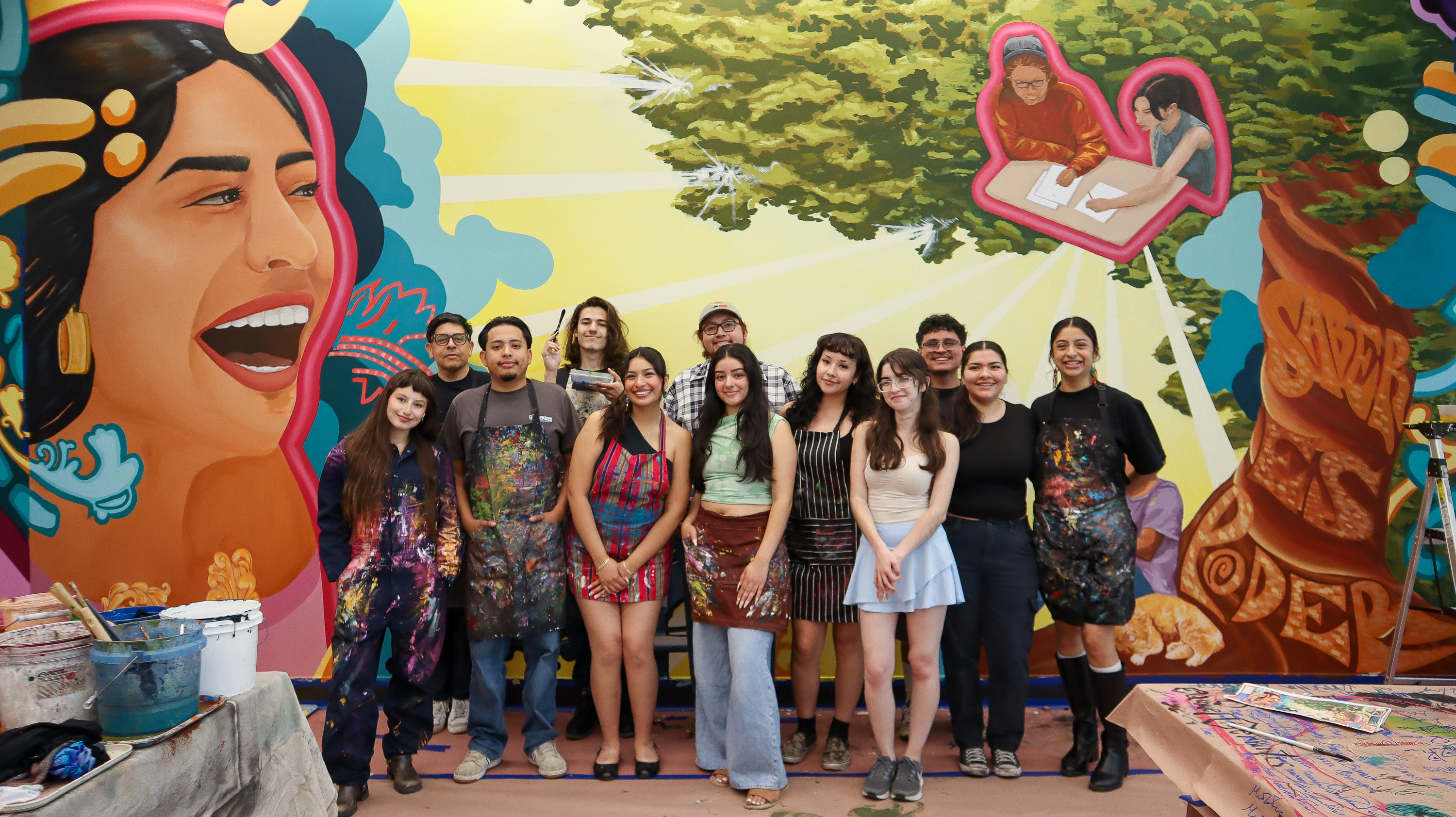 Group of people standing before vibrant mural.