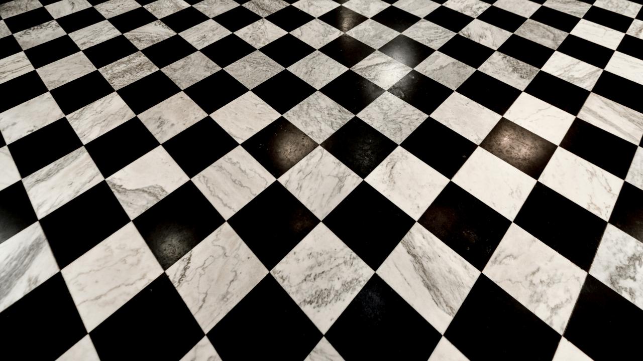 Worn black-and-white checkerboard floor tiles with stains receding diagonally