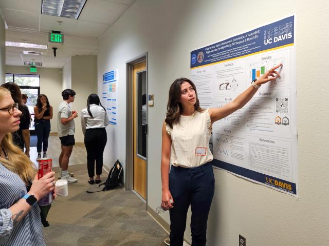 Valerie Klein talks about her research findings and point to a poster next to her on the wall