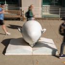 People pass by the Egghead 'Bookhead' sculpture, which features a head with its nose in a book