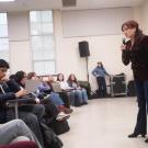 A speaker engaging with an audience in a lecture hall setting.