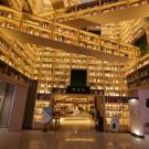 A modern library interior with illuminated wooden shelves filled with books.